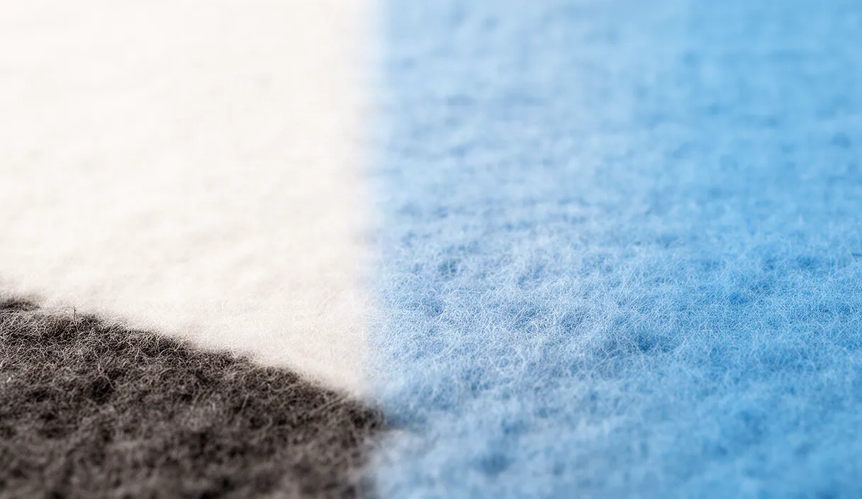 An extreme close-up of various fabric textures including wool, cotton, silk, and linen arranged to show the tactile details and material differences used in clothing.